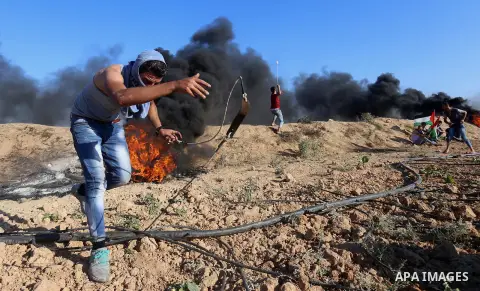 Palestinian protesters take cover during clashes with Israeli security forces following a demonstration against the blockade on the Gaza Strip, near the border fence east of Jabalia refugee camp on June 16, 2017. Photo b...