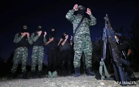 Palestinian militants from the Al-Quds Brigades, the armed wing of the Islamic Jihad movement perform prayer as they guard the border between the Gaza Strip and Israel on the Muslim holy fasting month of Ramadan on June...