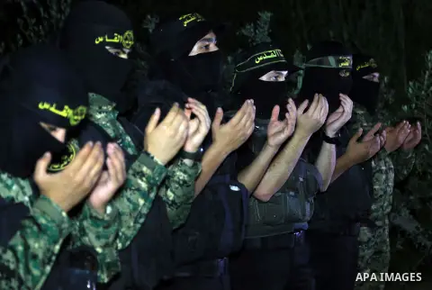 Palestinian militants from the Al-Quds Brigades, the armed wing of the Islamic Jihad movement perform prayer as they guard the border between the Gaza Strip and Israel on the Muslim holy fasting month of Ramadan on June...