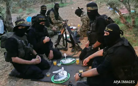 Palestinian militants from the Al-Quds Brigades, the armed wing of the Islamic Jihad movement break their fast as they guard the border between the Gaza Strip and Israel on the Muslim holy fasting month of Ramadan on Jun...