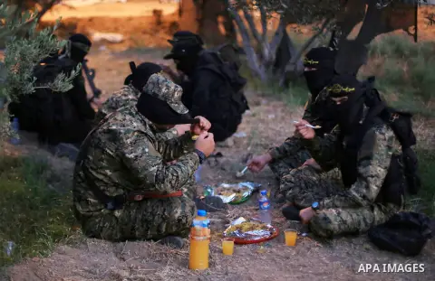 Palestinian militants from the Al-Quds Brigades, the armed wing of the Islamic Jihad movement break their fast as they guard the border between the Gaza Strip and Israel on the Muslim holy fasting month of Ramadan on Jun...