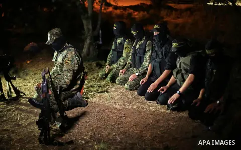 Palestinian militants from the Al-Quds Brigades, the armed wing of the Islamic Jihad movement perform prayer as they guard the border between the Gaza Strip and Israel on the Muslim holy fasting month of Ramadan on June...