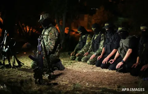 Palestinian militants from the Al-Quds Brigades, the armed wing of the Islamic Jihad movement perform prayer as they guard the border between the Gaza Strip and Israel on the Muslim holy fasting month of Ramadan on June...