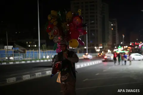 A Palestinian vendor sells balloons at the street during a power cut, in Gaza city on June 19, 2017. Photo by Mohammed Asad