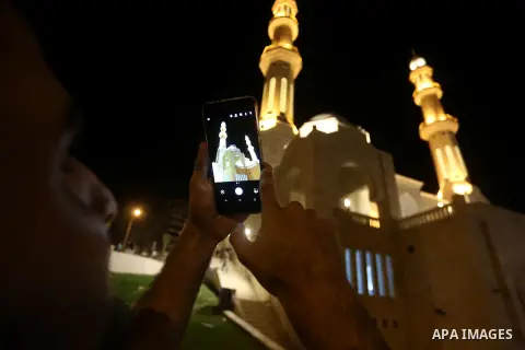 A Palestinian man takes photo to Mohammed Al Hassayna mosque as Palestinian laborers do construction work at night, on the Muslim holy fasting month of Ramadan, in Gaza city on June 20, 2017. Photo by Mohammed Asad