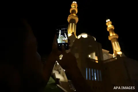 A Palestinian man takes photo to Mohammed Al Hassayna mosque as Palestinian laborers do construction work at night, on the Muslim holy fasting month of Ramadan, in Gaza city on June 20, 2017. Photo by Mohammed Asad