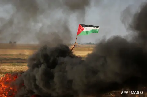 A protester holds a Palestinian flag during clashes with Israeli troops at a protest against reducing power supply to Gaza, near the border with Israel in Khan Younis in the southern Gaza Strip June 20, 2017. Photo by As...