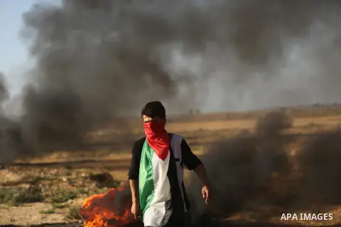 A protester covers his face with a Palestinian flag during clashes with Israeli troops at a protest against reducing power supply to Gaza, near the border with Israel in Khan Younis in the southern Gaza Strip June 20, 20...