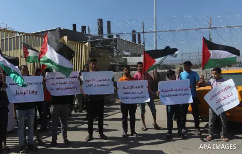 Palestinians hold banners during a protest against the worsening crisis of power outages in front of Gaza's power plant in Nuseirat in the center of Gaza strip, on June 21, 2017. Egypt began to deliver a million litres o...