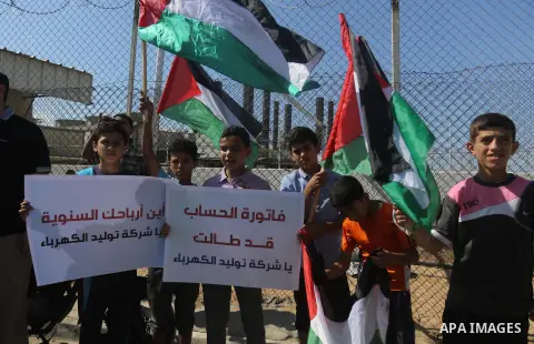 Palestinians hold banners during a protest against the worsening crisis of power outages in front of Gaza's power plant in Nuseirat in the center of Gaza strip, on June 21, 2017. Egypt began to deliver a million litres o...