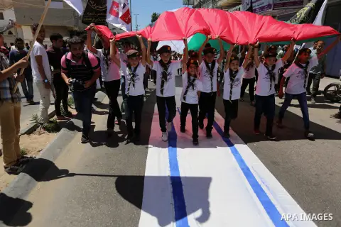 Palestinian Scout youths wave a large Palestinian flag and step on the Israeli flag in a protest marking the annual al-Quds Day, or Jerusalem Day, following Friday prayer in Gaza city June 23, 2017. Photo by Ashraf Amra