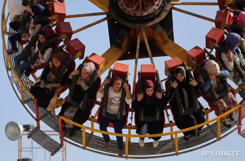 Palestinians take a ride at an amusement park on the third day of Eid al-Fitr holiday which marks the end of the Muslim holy month of Ramadan, in Gaza City on June 27, 2017. Photo by Ashraf Amra