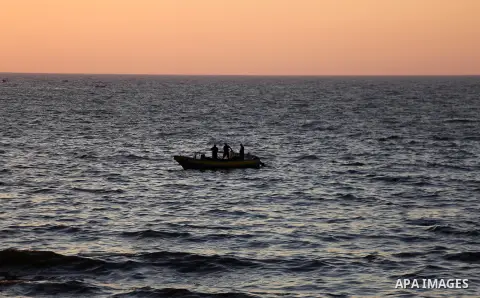 Palestinian fishermen ride a fishing boat during the sunset on the beach of Gaza city, on June 29, 2017. Photo by Mohammed Asad
