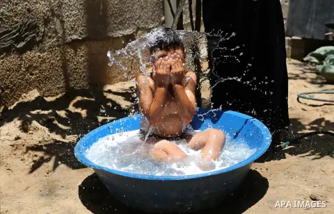 A Palestinian woman washes her son outside her house during a heatwave in Beit Lahia in the northern of Gaza Strip, on July 4, 2017. Photo by Ashraf Amra