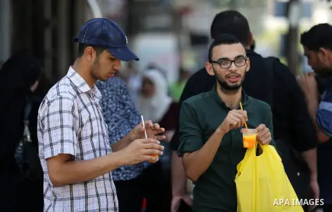 Palestinians eat ice-cream (sundae) in the street during a heatwave in Gaza city on July 4, 2017. Photo by Ashraf Amra