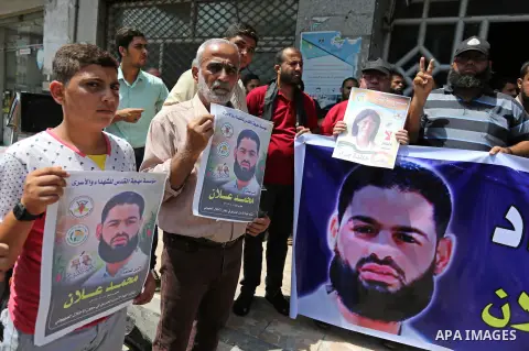 Palestinian supporters of the Islamic Jihad Movement, hold placards during a protest to show solidarity with Palestinian prisoners held in Israeli Jails, in Gaza city, on July 5, 2017. Photo by Ashraf Amra