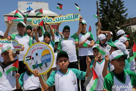 Palestinian children hold the national flags during the announcement the start of summer camps organized by the Hamas movement in Gaza city on July 8, 2017. Photo by Ashraf Amra