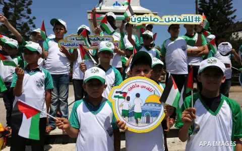 Palestinian children hold the national flags during the announcement the start of summer camps organized by the Hamas movement in Gaza city on July 8, 2017. Photo by Ashraf Amra