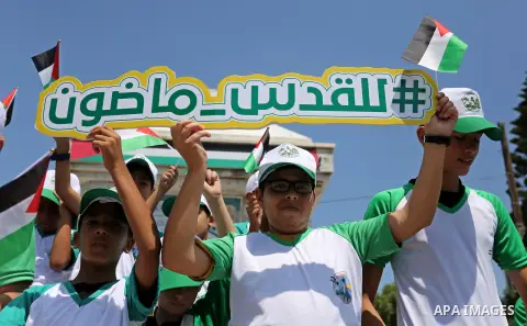 Palestinian children hold the national flags during the announcement the start of summer camps organized by the Hamas movement in Gaza city on July 8, 2017. Photo by Ashraf Amra