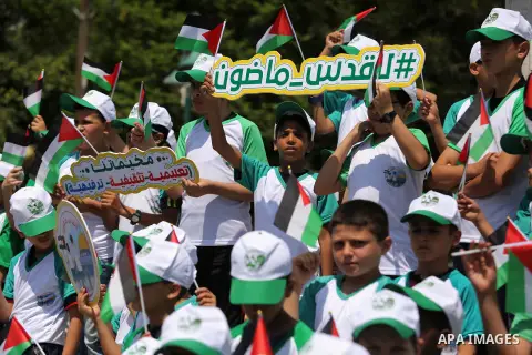 Palestinian children hold the national flags during the announcement the start of summer camps organized by the Hamas movement in Gaza city on July 8, 2017. Photo by Ashraf Amra