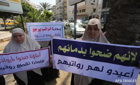 Palestinian Martyrs Families hold placards during a protest demanding their salaries in Gaza city on July 26, 2017. Photo by Mohammed Asad