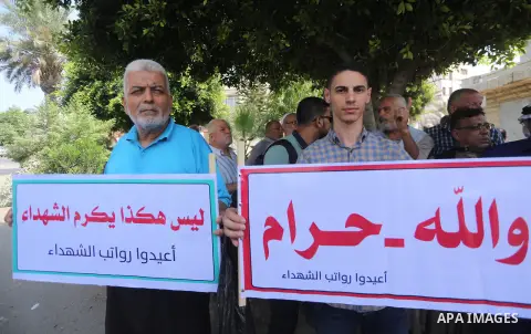Palestinian Martyrs Families hold placards during a protest demanding their salaries in Gaza city on July 26, 2017. Photo by Mohammed Asad
