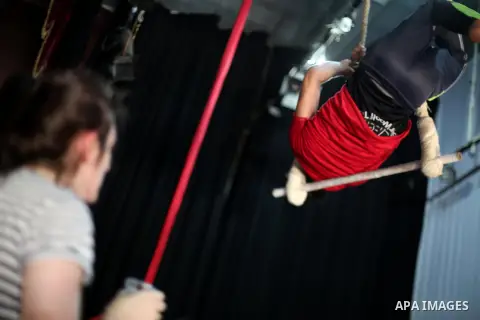 An Irish trainer, Jennifer Higgins, helps a member of Gaza circus to perform during an aerial silks practice class in Gaza City, on August 3, 2017. Photo by Mohammed Asad