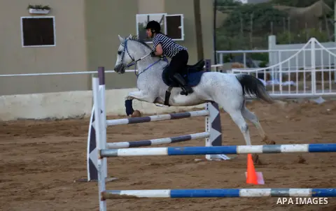 A Palestinian girl rides her horse during a jump obstacles championship, in Gaza city on August 4, 2017. Photo by Mohammed Asad