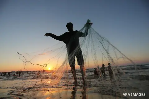 A Palestinian fisherman pulls his nets on a beach in Gaza City on August 4, 2017. Photo by Ashraf Amra