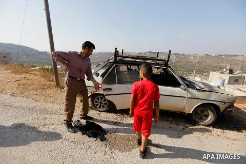Palestinians from the village of Umm Safa, west of Ramallah in the occupied West Bank, check a vehicle that was set ablaze on August 9, 2017 after Israeli settlers reportedly vandalised the Palestinian village calling fo...