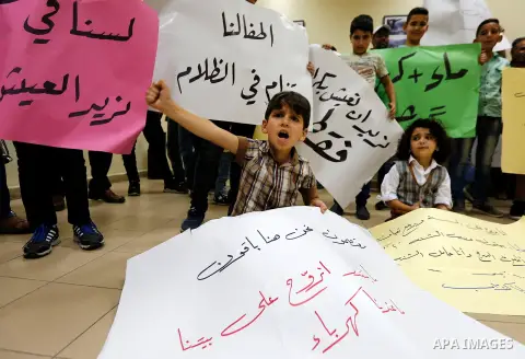 Palestinian children hold placards during a protest against the power and water crisis, at Hebron municipality, in the West Bank city of Hebron on August 9, 2017. Photo by Wisam Hashlamoun