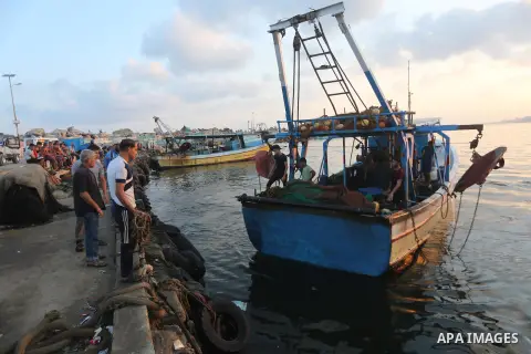 Palestinian fishermen ride a fishing boat, in Gaza seaport, on August 10, 2017. Photo by Mohammed Asad