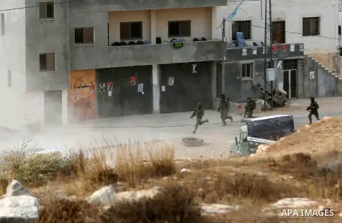 Israeli soldiers run near the house of a Palestinian assailant after it was demolished by Israeli troops in the West Bank village of Deir Abu Mashal, near Ramallah, on August 10, 2017. Israeli authorities have demolished...