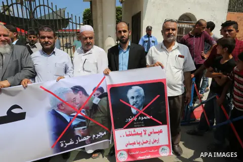 Palestinians hold a poster depicting Palestinian President Mahmoud Abbas during a protest against the blockade on Gaza strip and demanding their salaries in Gaza City on August 10, 2017. Photo by Ashraf Amra