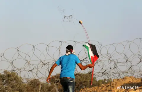 A Palestinian protester uses slingshots to hurl stones towards Israeli security forces during clashes near the border between Israel and Central Gaza Strip August 11, 2017. Photo by Ashraf Amra