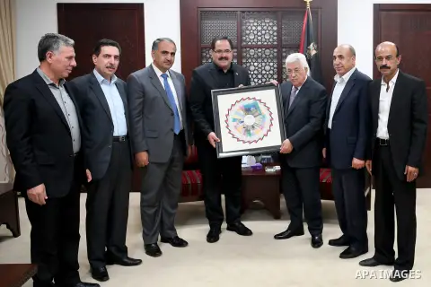 Palestinian President Mahmoud Abbas receives the first edition of the curriculum, at his headquarter, in the West Bank city of Ramallah, on August 12, 2017. Photo by Osama Falah