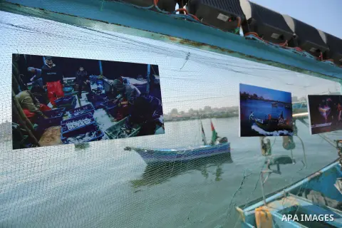 Palestinians attend a photo gallery on fishing boat, in Gaza seaport, on August 23, 2017. Photo by Ashraf Amra