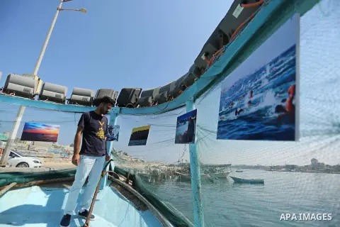 Palestinians attend a photo gallery on fishing boat, in Gaza seaport, on August 23, 2017. Photo by Ashraf Amra