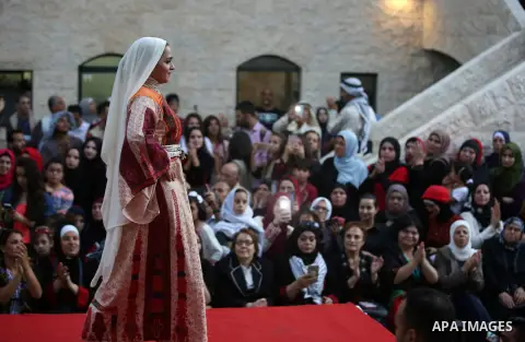A Palestinian woman wearing traditional dress creation takes part during a fashion show marking Traditional Palestinian Dress Day, in the West Bank city of Nablus on August 22, 2017. Photo by Ayman Ameen