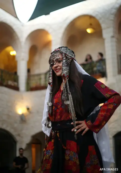 A Palestinian woman wearing traditional dress creation takes part during a fashion show marking Traditional Palestinian Dress Day, in the West Bank city of Nablus on August 22, 2017. Photo by Ayman Ameen