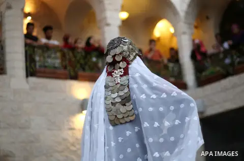 A Palestinian woman wearing traditional dress creation takes part during a fashion show marking Traditional Palestinian Dress Day, in the West Bank city of Nablus on August 22, 2017. Photo by Ayman Ameen