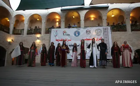 Palestinian women wearing traditional dress creation take part during a fashion show marking Traditional Palestinian Dress Day, in the West Bank city of Nablus on August 22, 2017. Photo by Ayman Ameen