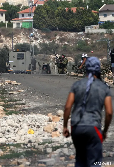 A Palestinian protester hurls stones towards Israeli security forces during clashes following a weekly demonstration against the expropriation of Palestinian land by Israel in the village of Kfar Qaddum, near Nablus in t...