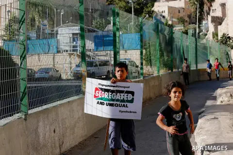 Palestinian protesters hold placards during a protest against new gates and barriers near the near the Ibrahimi mosque in the Old city of the West Bank city of Hebron on August 28, 2017. Photo by Wisam Hashlamoun