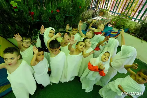 Palestinian children gather around a makeshift cube representing the holy Kaaba, in the West bank city of Hebnron, on August 30, 2017, as part of training children how to perform Hajj pilgrimage. Muslims from around the...