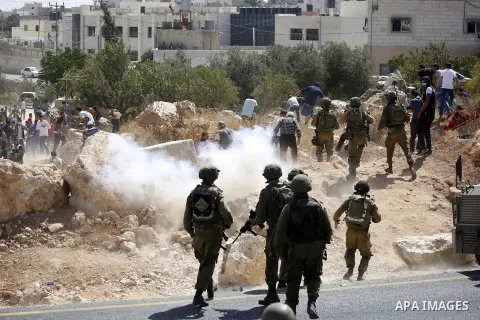 Palestinian run for cover from sound grenades during clashes following a protest against closure of a road south of the West Bank city of Hebron September 22, 2017. Photo by Wisam Hashlamoun