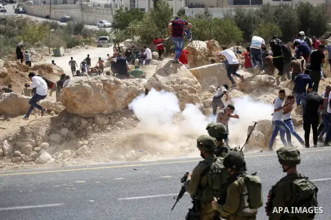 Palestinian run for cover from sound grenades during clashes following a protest against closure of a road south of the West Bank city of Hebron September 22, 2017. Photo by Wisam Hashlamoun