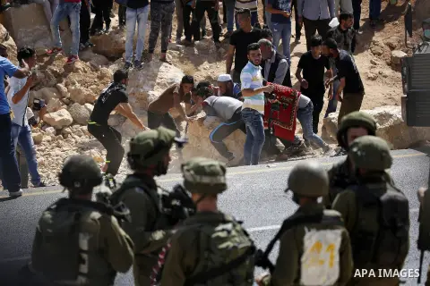 Palestinians remove a rock during protest against closure of a road by Israeli troops south of the West Bank city of Hebron September 22, 2017. Photo by Wisam Hashlamoun