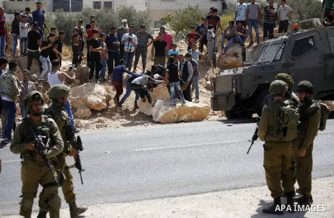 Palestinians remove a rock during protest against closure of a road by Israeli troops south of the West Bank city of Hebron September 22, 2017. Photo by Wisam Hashlamoun