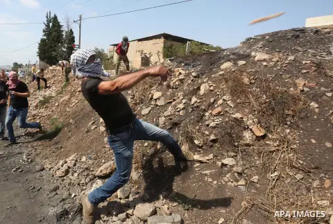 A Palestinian protester throws a stone towards Israeli security forces during clashes following a demonstration against the expropriation of Palestinian land by Israel in the village of Kfar Qaddum, near Nablus in the oc...